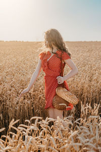 Rear view of woman standing on field against sky