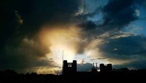 Low angle view of silhouette building against cloudy sky