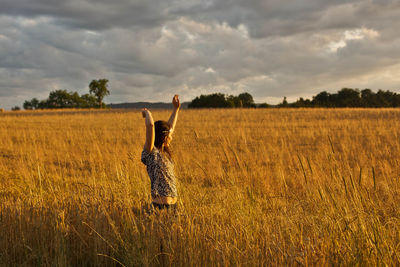 Full length of woman with arms raised in field