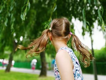 Side view of girl with pigtails against trees at park