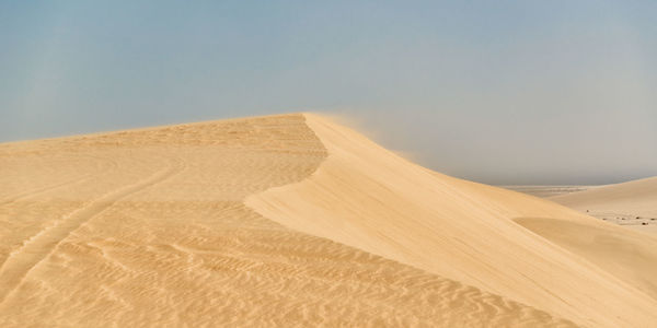 Sand dunes in desert against clear sky