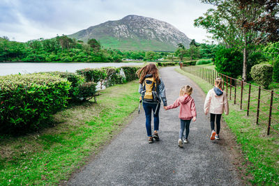 Rear view of woman with daughters walking on road