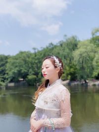 Portrait of young woman standing against lake