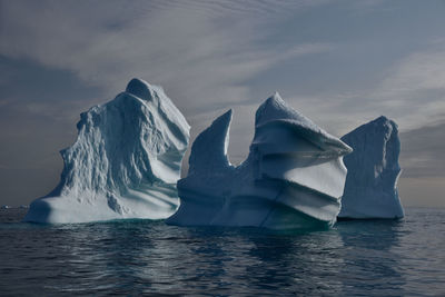 Icebergs on sea against sky during winter