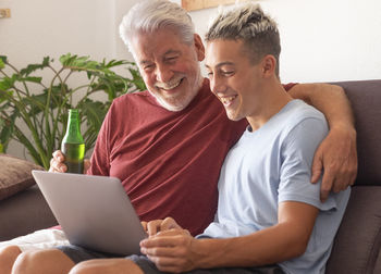 Smiling senior man with boy using laptop at home