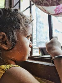 Close-up portrait of girl looking through window