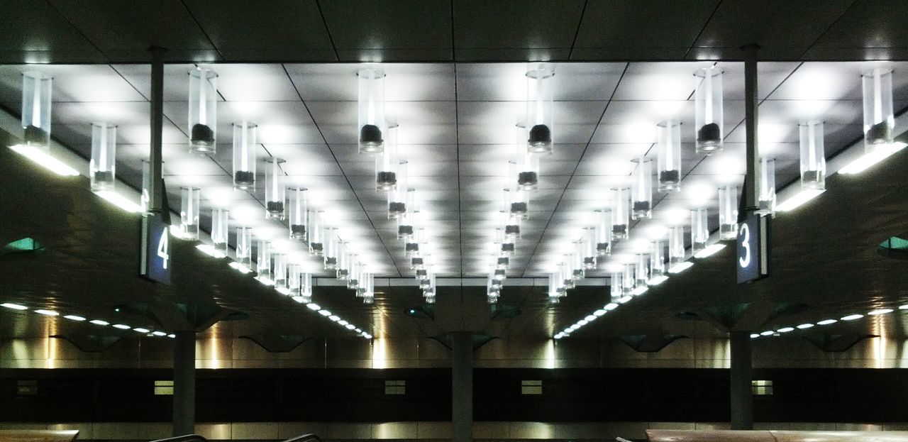 indoors, in a row, illuminated, repetition, order, architecture, side by side, built structure, lighting equipment, no people, ceiling, modern, arrangement, large group of objects, reflection, empty, window, shelf, technology, glass - material