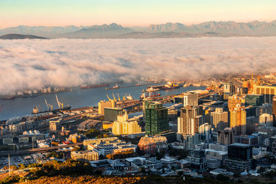 Aerial view of cityscape against sky during sunset with wall of fog 