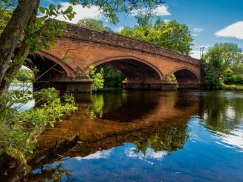 Arch bridge over river against sky