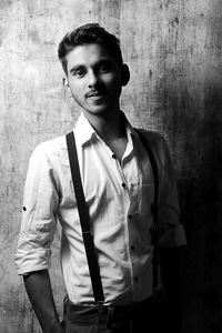 Portrait of young man standing against wall