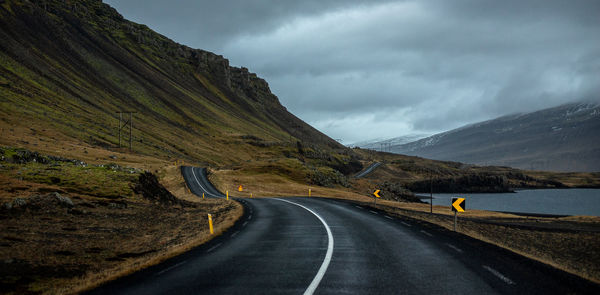 Dramatic winding road by mountain against sky