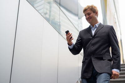 Low angle view of businessman standing by wall