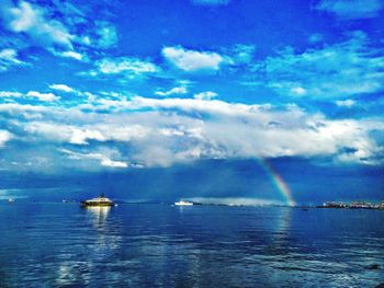 Scenic view of rainbow over sea against sky