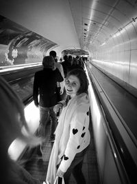 Portrait of woman with crowd on illuminated moving walkway