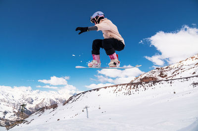 Low angle view of man skiing on snowcapped mountain against clear sky