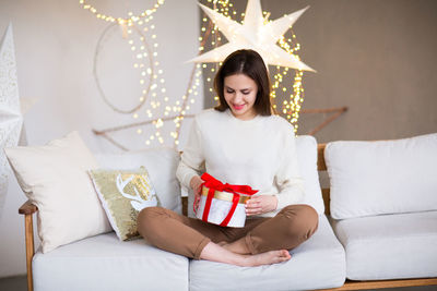 Young woman sitting on sofa at home