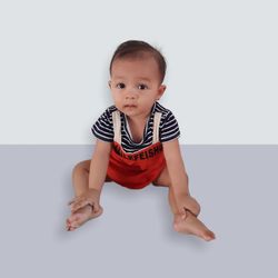 Portrait of cute baby sitting against white background