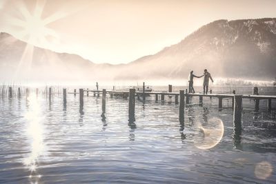 Men fishing in lake against sky