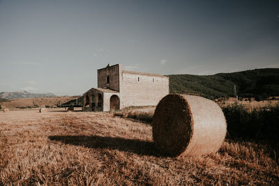 Hay bales on field against clear sky