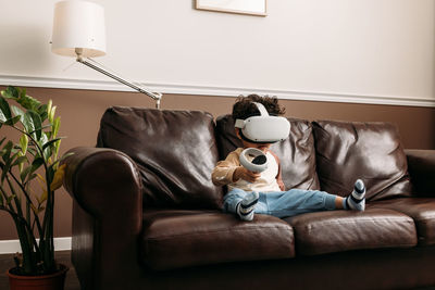 Cute boy playing game while wearing virtual reality simulator