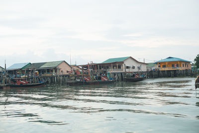 Buildings at waterfront against cloudy sky