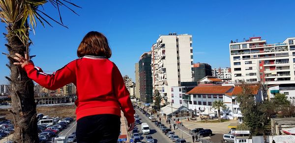 Rear view of girl walking against buildings in city