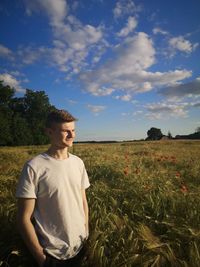 Young man standing on field against sky