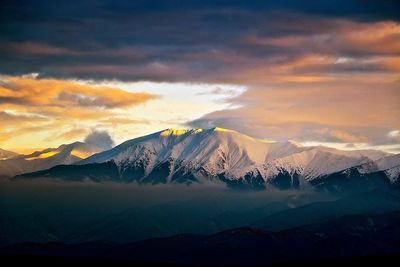 Scenic view of snow covered mountain against cloudy sky