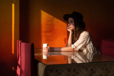 Portrait of young woman in hat sit alone in cafe