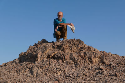 Senior man sitting on rock in the desert 