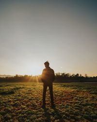 Rear view of silhouette man standing on land against sky during sunset