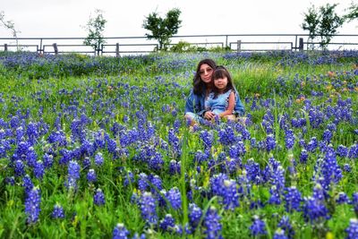 Portrait of woman standing amidst purple flowering plants on field