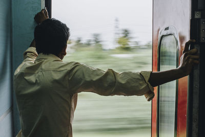 Rear view of man standing by train window