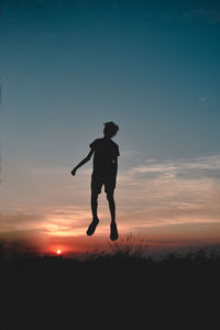 Low angle view of silhouette woman standing against sky during sunset