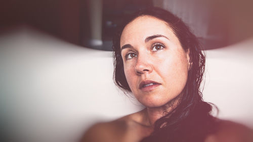 Mature woman looking away while sitting in bathtub