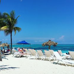 Lounge chairs on beach against blue sky