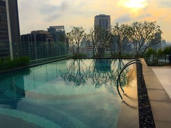 Reflection of trees in swimming pool against sky