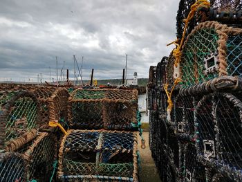 Stack of fishing net at harbor against sky