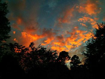Silhouette trees against dramatic sky during sunset