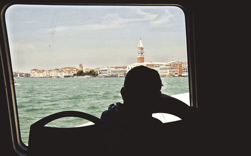 Rear view of woman sitting on boat in sea