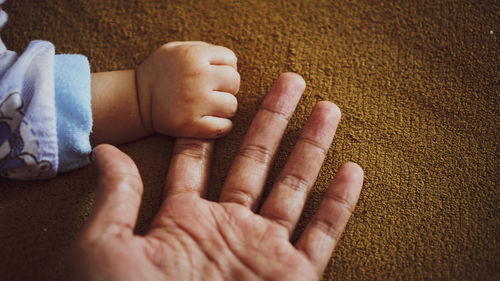 Cropped image of man holding baby boy hand