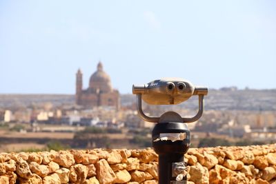 Close-up of coin-operated binoculars against buildings in city