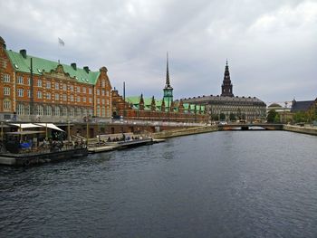 River by borsen building against cloudy sky