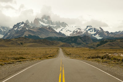 Empty road leading towards mountains during winter