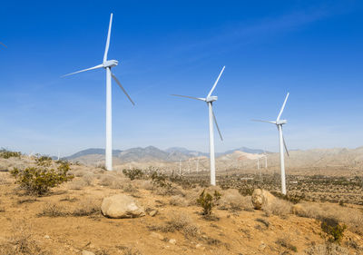 Windmills on field against sky