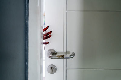 Cropped bloody hand of woman by door