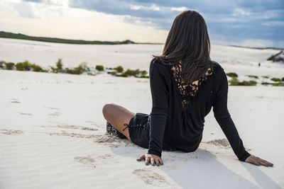 Rear view of woman sitting on beach