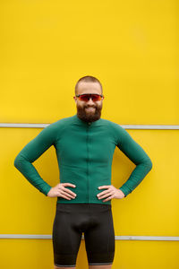 Portrait of young man standing against yellow wall