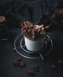 Cinnamon sticks in an old metal mug on a black table. aromatic spice