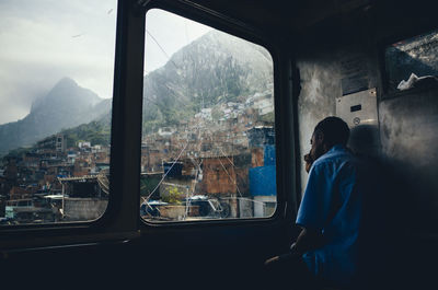 Rear view of boy looking through window